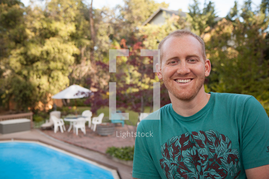 man sitting outdoors in front of a pool 