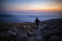 man hiking on a mountaintop at dawn 