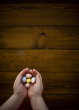 cupped hands holding candy Easter eggs 