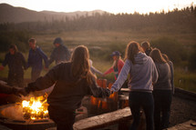 teens holding hands around a bonfire 