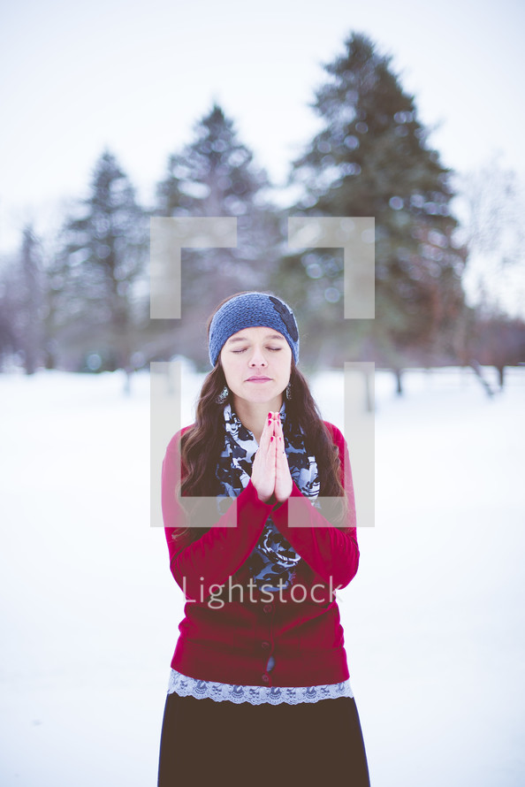 a woman praying outdoors in winter 