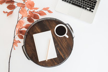 wooden tray, fall foliage, journal, pencil, coffee mug, and laptop on a desk 