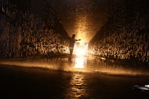 man standing in a wet glowing tunnel with open arms 