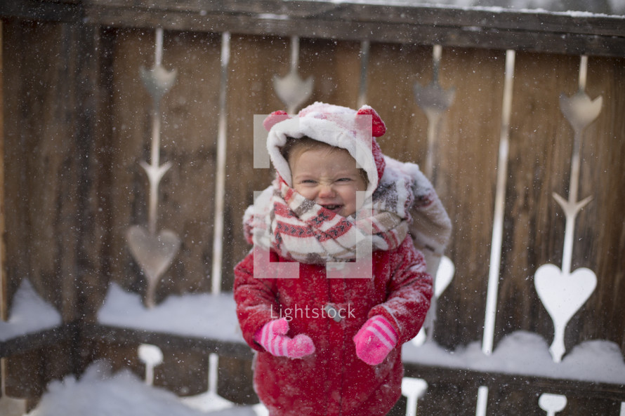 a toddler girl in a winter coat playing in snow 