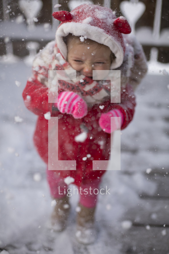 a toddler girl playing in snow but doesn't like it 