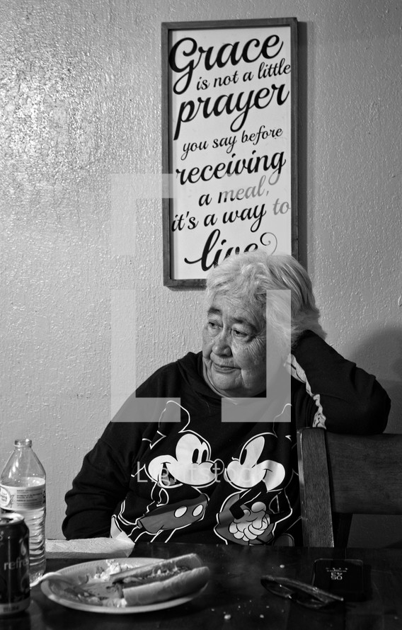elderly woman sitting at a dinner table 