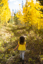 little girl walking under golden fall foliage 