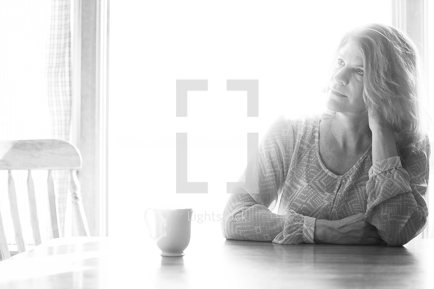 Woman having coffee at the breakfast table in the morning sun.