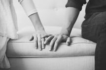 Couple's hands on a sofa.