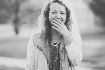 teenage girl laughing with her hand covering her mouth.