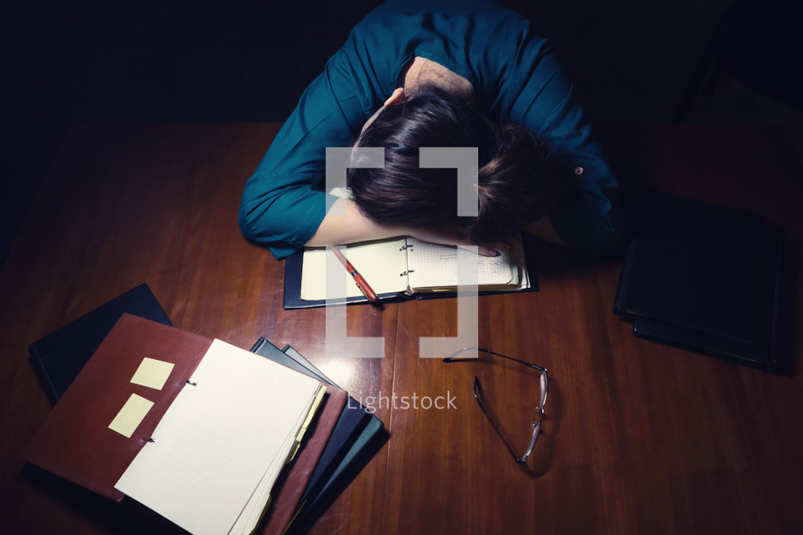 an exhausted woman with her head on her desk 