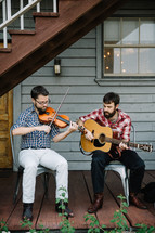 men playing a fiddle and guitar outdoors 