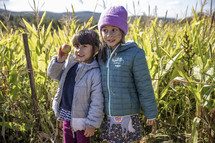 Sisters in a corn field with an apple