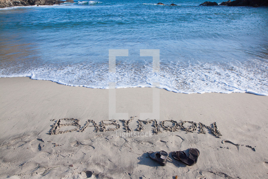 babymoon written in the sand on a beach 