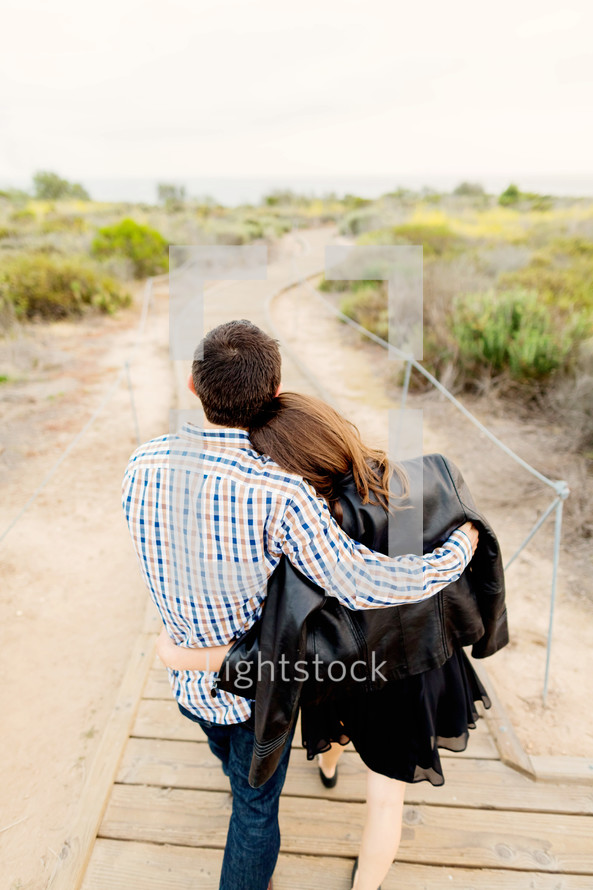 Couple embracing as they walk along the boardwalk.