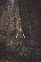 man standing in front of a rock wall 