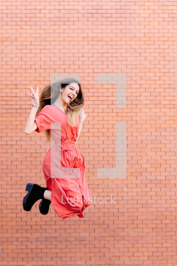 young woman jumping up wearing red dress