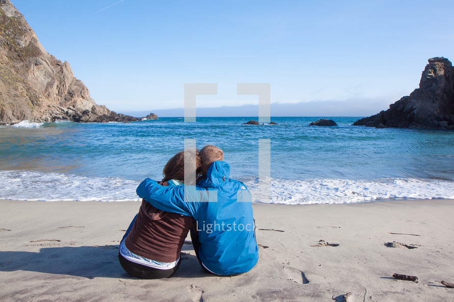 couple hugging sitting on a beach 