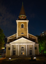 lights shining on a city church at night 