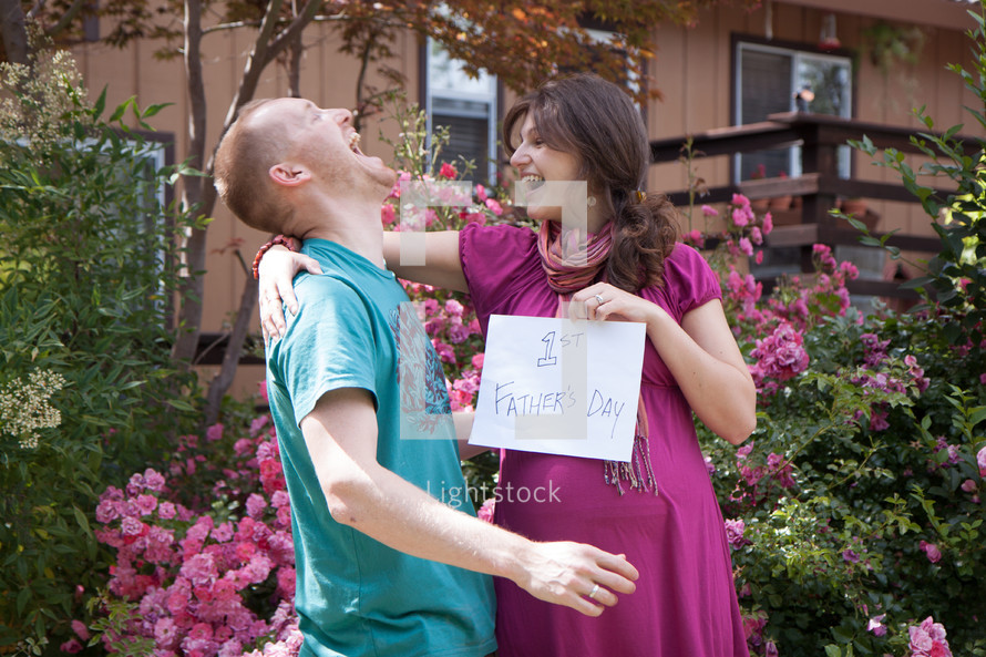 pregnant woman holding a first father's day sign 