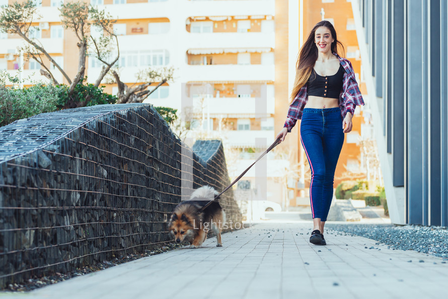 a woman with a small dog on a leash 
