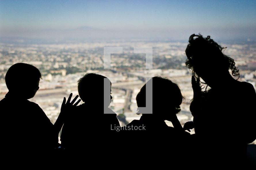 silhouettes of children looking out a window 