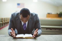 a man reading a Bible at an altar of a church 