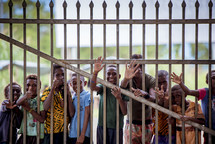 kids waving through a fence 