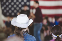 girl in a cowboy hat watching a speaker on stage 