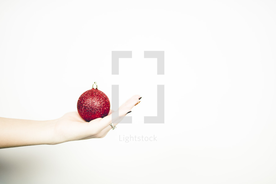 cupped hand holding a red Christmas ornament 