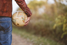man holding a globe outdoors 