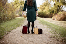 a woman holding a globe and Bible standing next to luggage 
