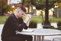 a man praying over the pages of an opened Bible 