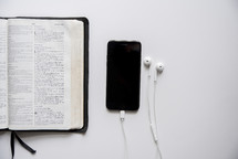phone, earbuds, and opened Bible 