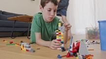 Young boy playing and constructing with toy bricks on the living room floor