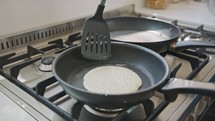 Young kids preparing pancakes in the kitchen using a frying pan