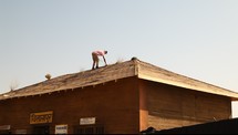 a man gathering sticks off of a roof 