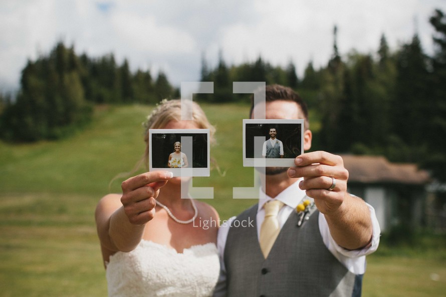 bride and groom holding up polaroid photos 