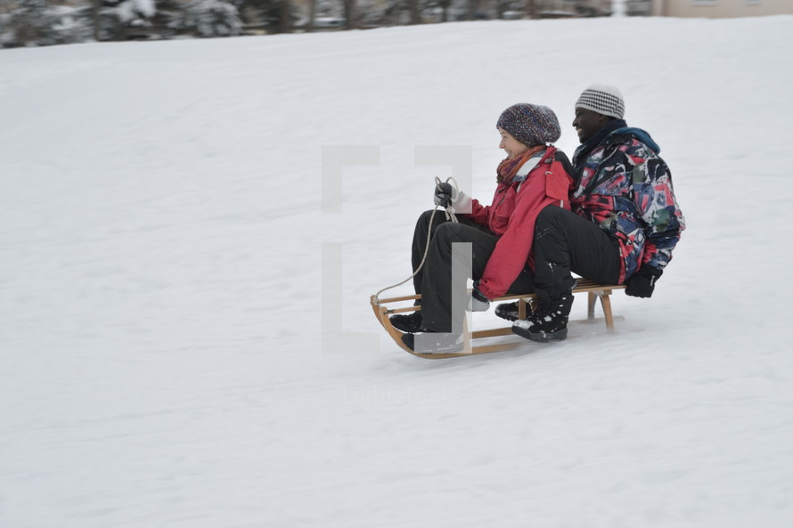 laughing couple sledding together