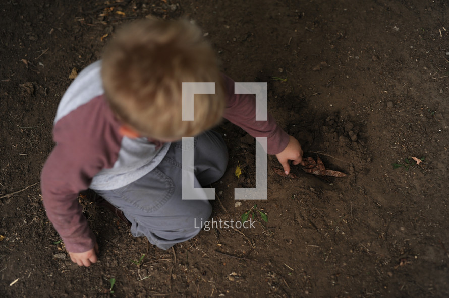 a boy child playing in the the dirt 
