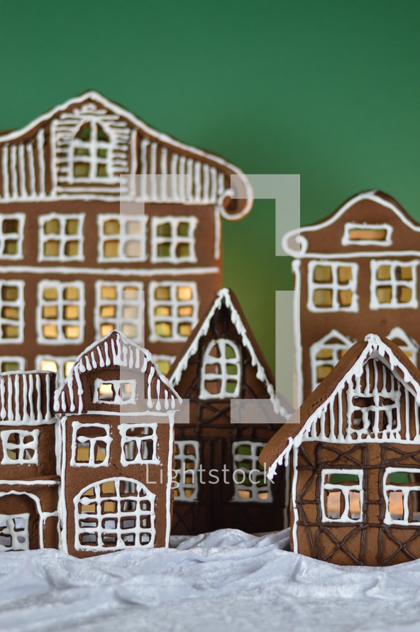 home made gingerbread village in front of green background on white snowlike velvet as advent decoration