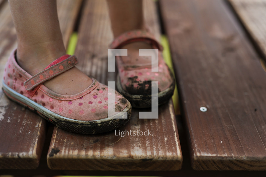 a little girl with muddy shoes 