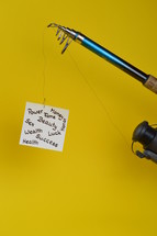 temptation – a piece of paper with words for baits written on at the fishhook of an  angling rod
