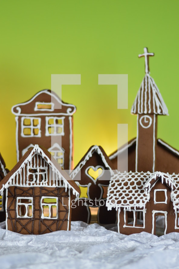 home made gingerbread village in front of yellow and green background on white snowlike velvet as advent decoration