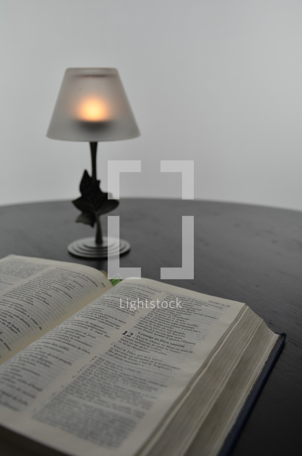 votive candle shaded lamp and an open Bible
