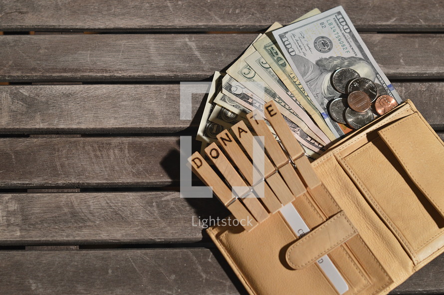 Open purse with money flowing out attached to wooden clothespins with the word DONATE burnt into.
