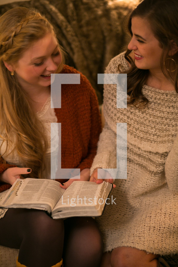 Two young women reading the Bible together.