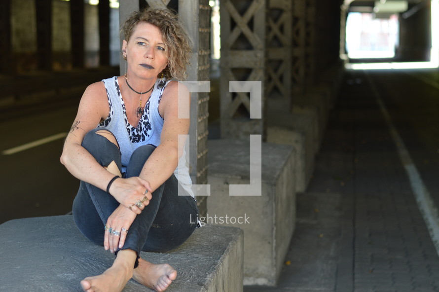 self-confident punk woman sitting under an overpass 
