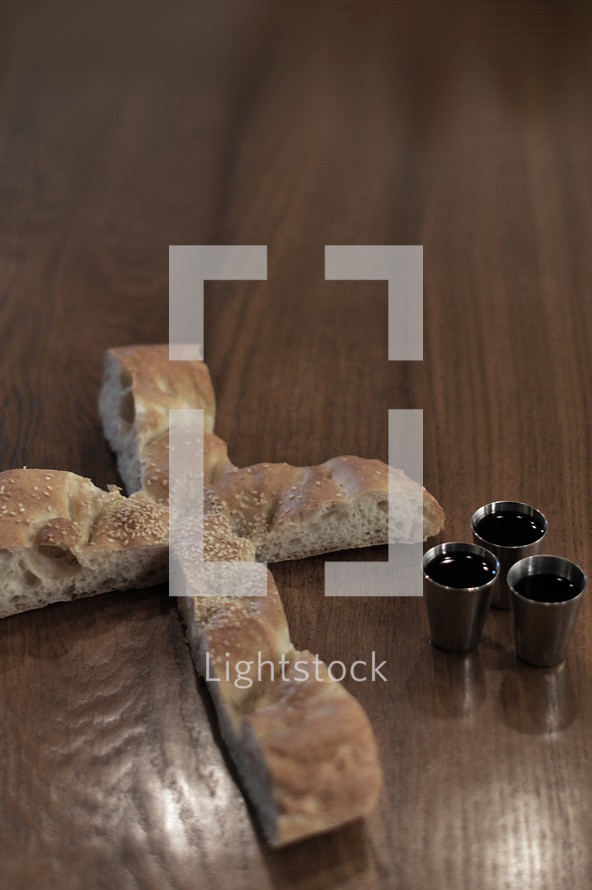 Bread in the shape of a cross with three goblets of wine