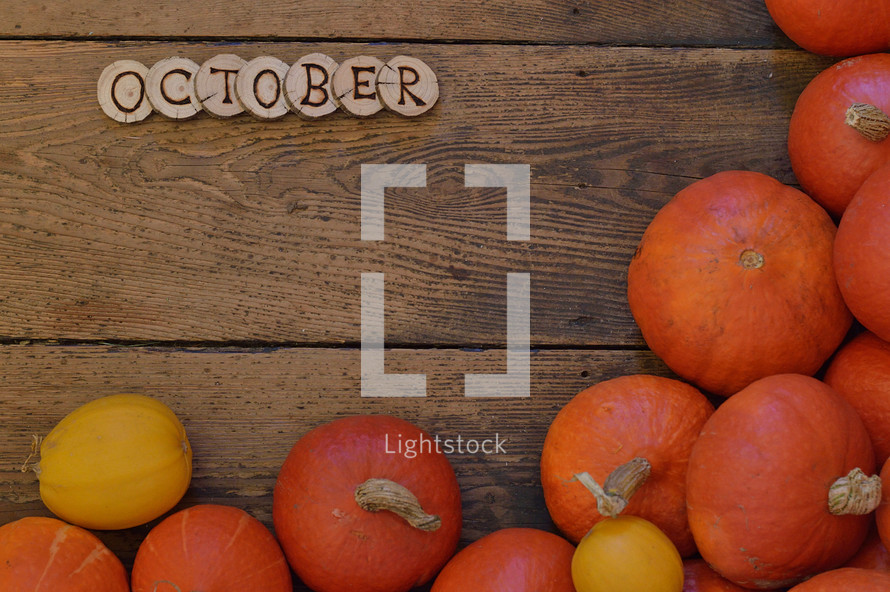 Pumpkins on wooden planks with pieces of wood spelling the word OCTOBER
